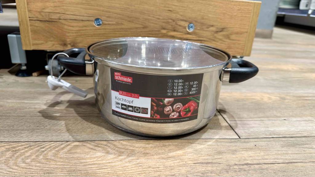 Getestet: Ein Kochtopf mit 20 cm Durchmesser steht eingeschweißt in Kunststofffolie auf dem Boden in einem Geschäft.