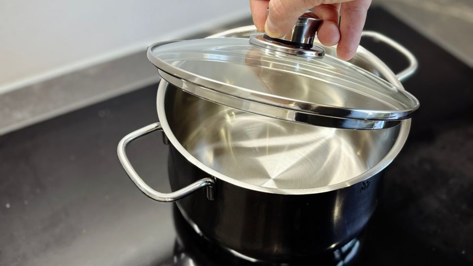 Kochtopf-Test: Eine Person nimmt den Deckel vom WMF-Kochtopf.