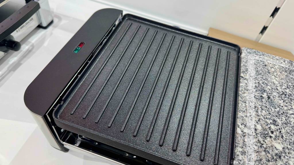 Nahaufnahme der geriffelten, schwarzen Grillplatte eines Raclette-Grills mit Steinplatte im Test.
