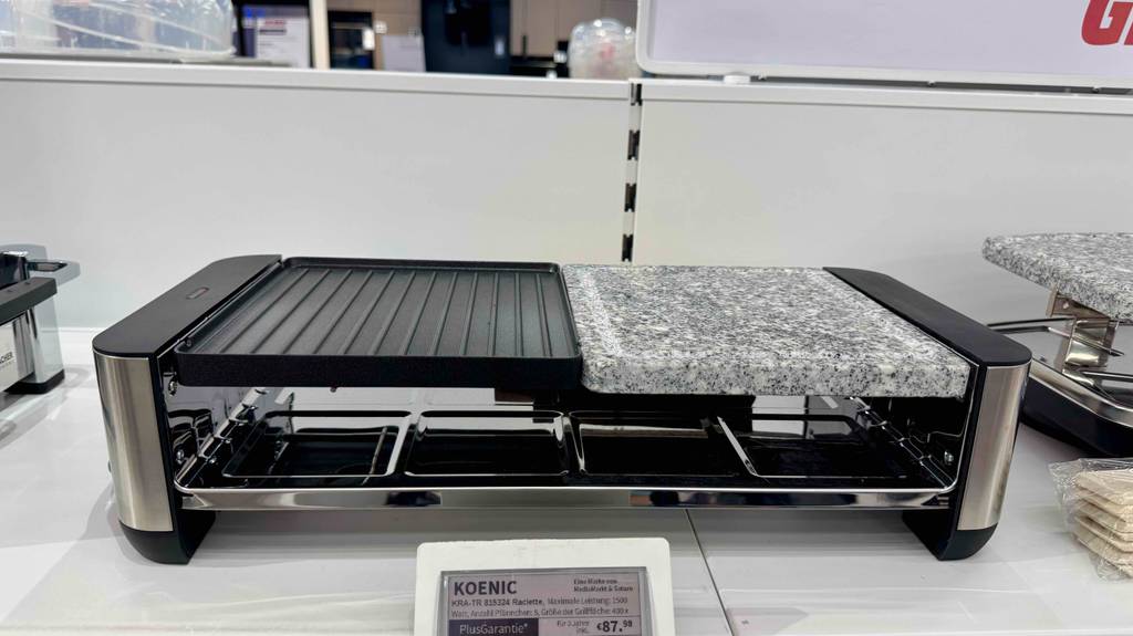 Der getestete Raclette-Grill mit Steinplatte steht inklusive Preisschild auf einem Ausstellungsregal im Geschäft zwischen zwei weiteren Grills.