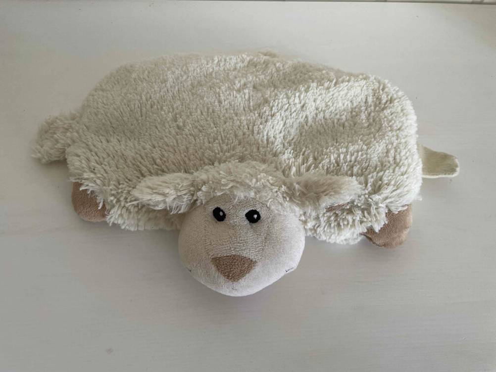 Ein getestetes Körnerkissen in Form eines Pluschschafes auf einer hellen Fläche.