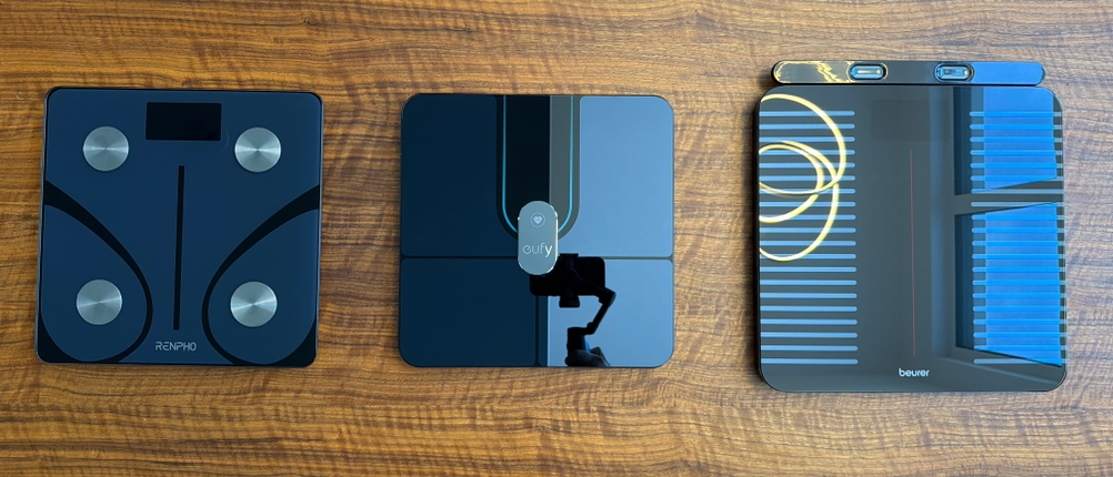 Drei Körperfettwaagen stehen nebeneinander auf einem Holzboden.