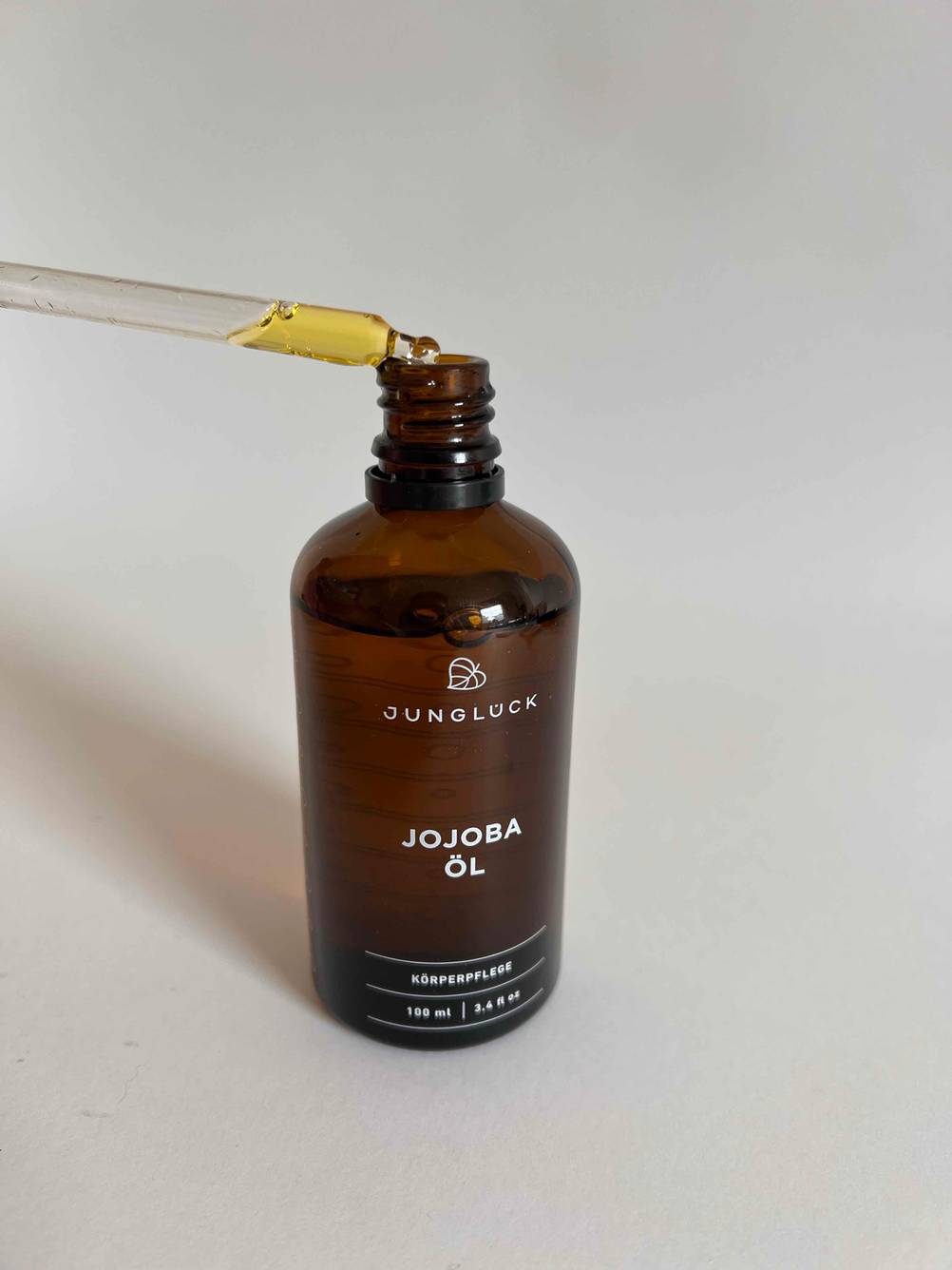 Ein getestetes Körperöl befindet sich mit einer Pipette in einer Glasflasche. 