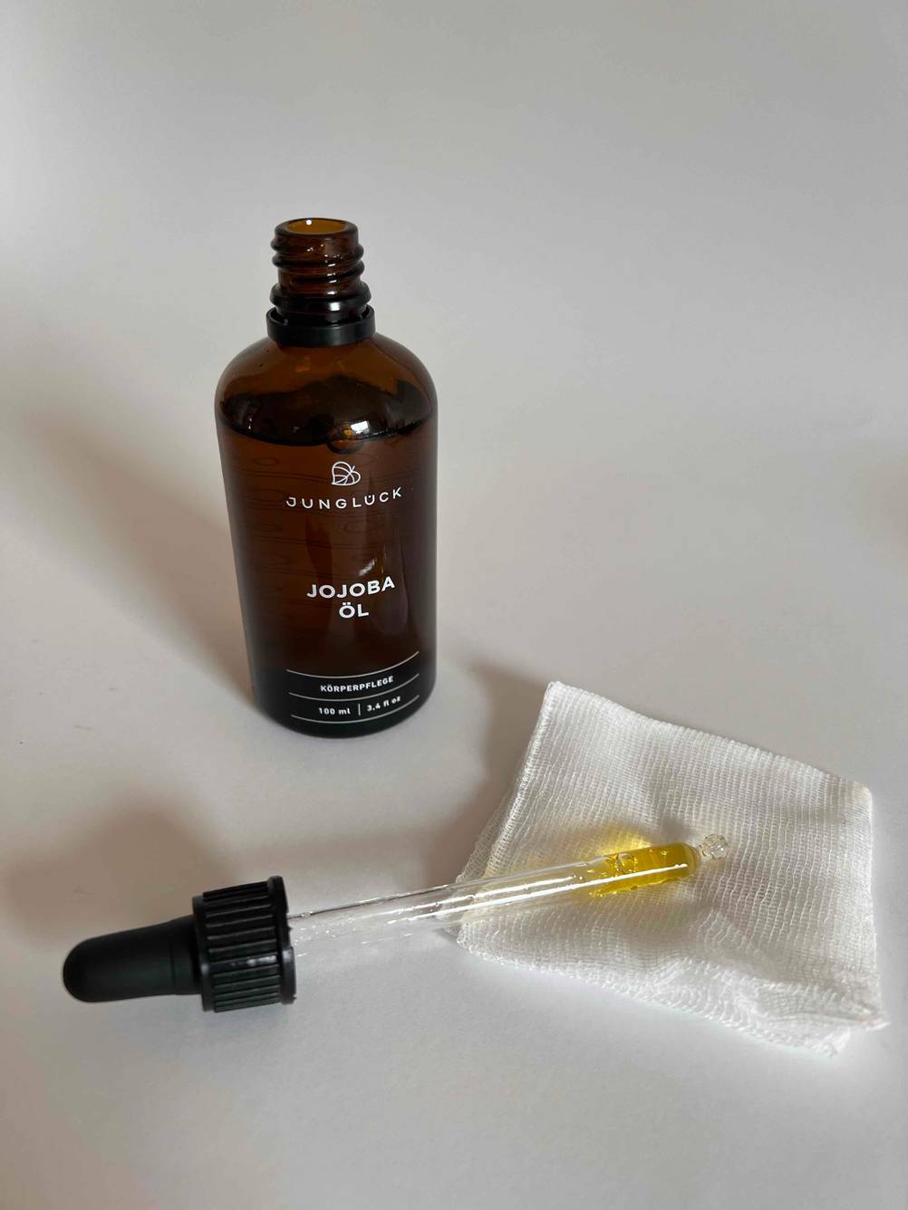 Ein getestetes Körperöl befindet sich abgefüllt in einer Glasflasche vor einer Pipette. 