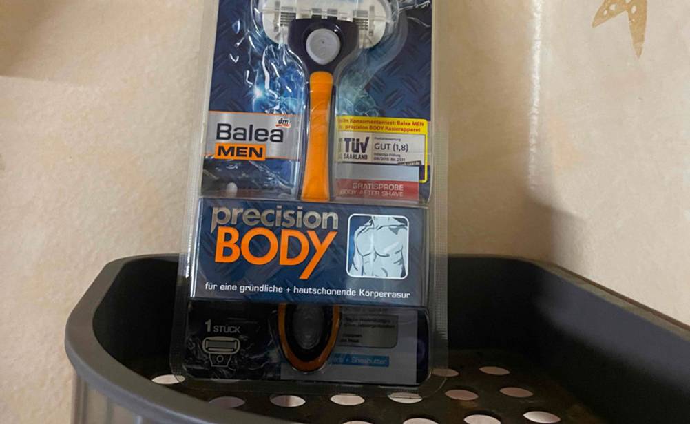 Nahaufnahme der Originalverpackung des getesteten Körperrasierers auf einer dunklen Schale an der Wand.