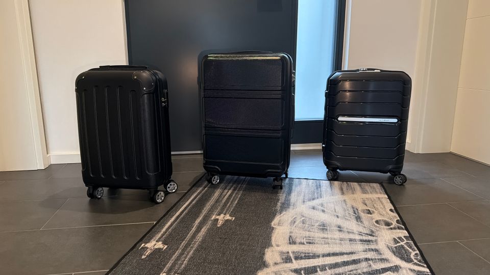 Drei Koffer stehen nebeneinander auf einem Teppich