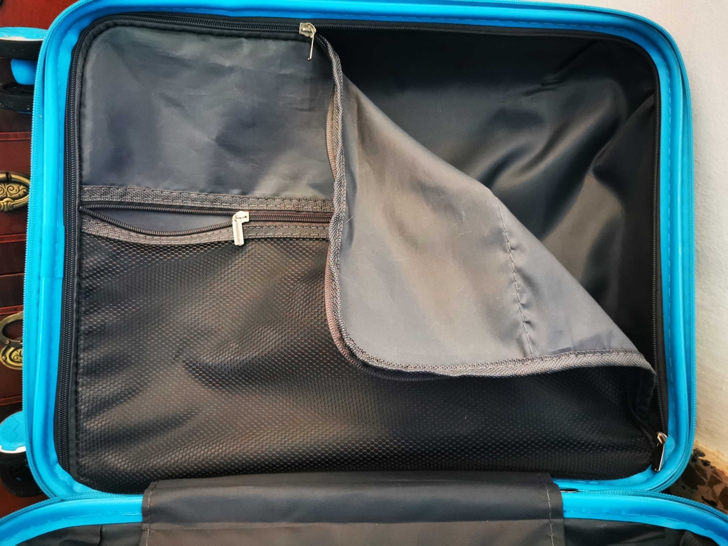 Koffer-Test: Ein türkisfarbenes Modell mit Fokus auf den Reißverschluss im Innenraum liegt geöffnet vor der Kommode.