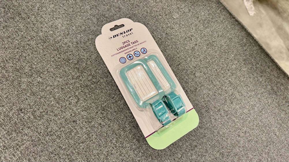 Auf einem grauen Stoff liegt eine Packung mit den Kofferanhängern im Test.