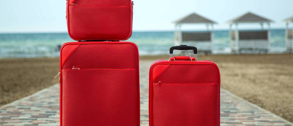 Kofferset Weichschale im Test: 3 unterschiedlich große rote Koffer auf einem gepflasterten Strandweg