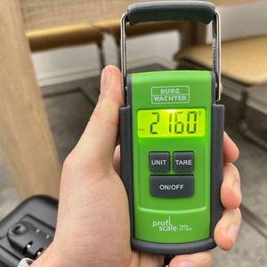 Eine Burg-Wächter-Tara-PS-7600-Kofferwaage zeigt während des Wiegens eines Koffers einen stabilisierten Messwert im Display.