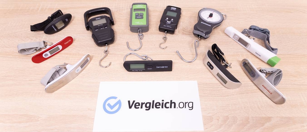 Kofferwaagen im Test: Viele Kofferwaagen liegen auf einem Holztisch.