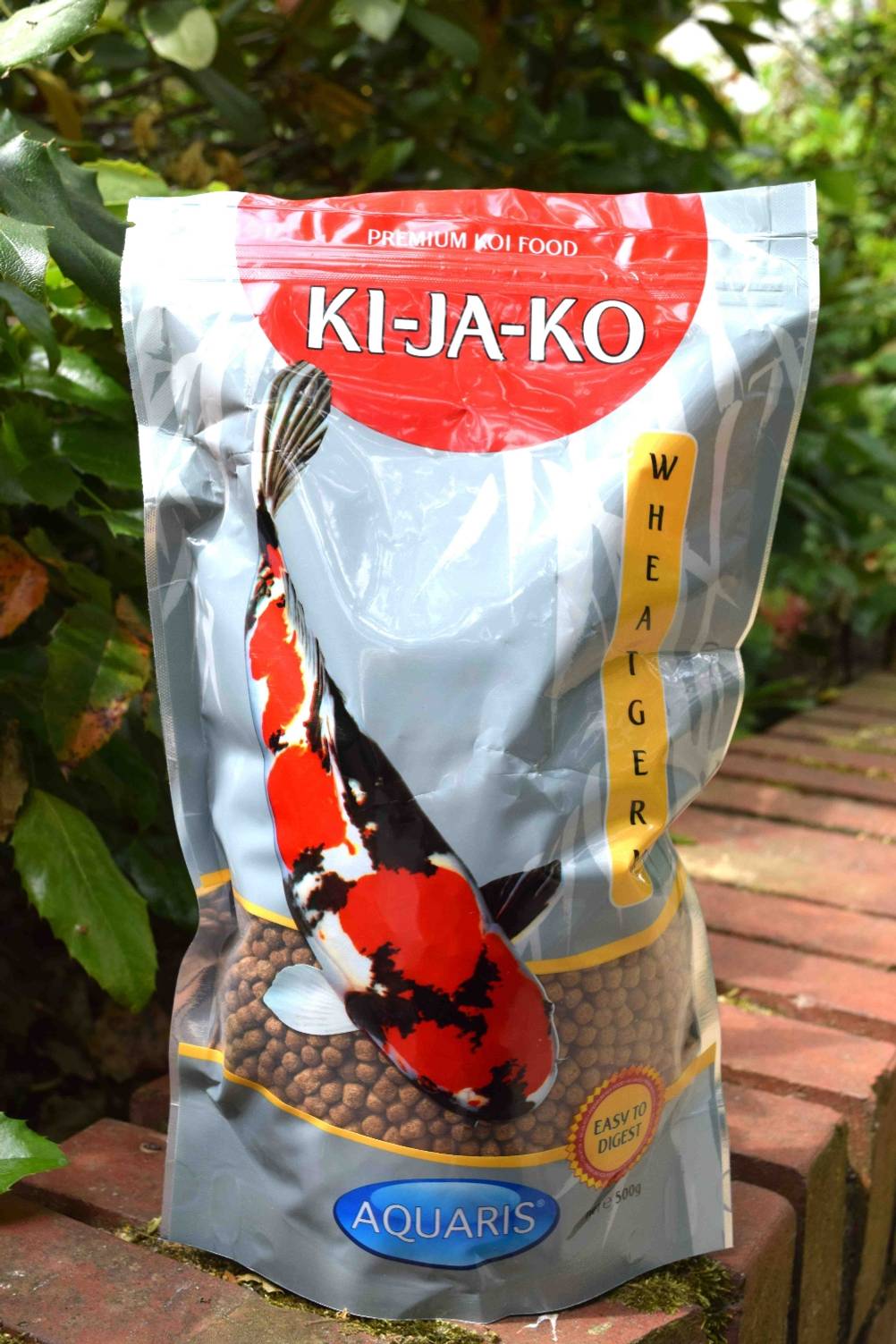 Eine Verpackung mit getesteten Koifutter-Pellets steht im Garten. 