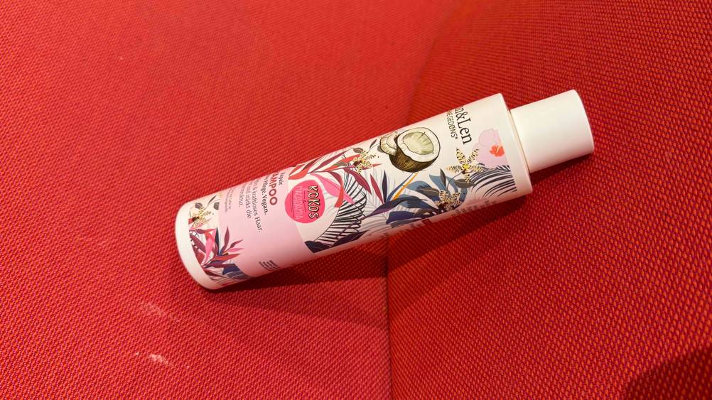 Kokos-Shampoo im Test: Seitenansicht der Flasche auf einem roten Polster.