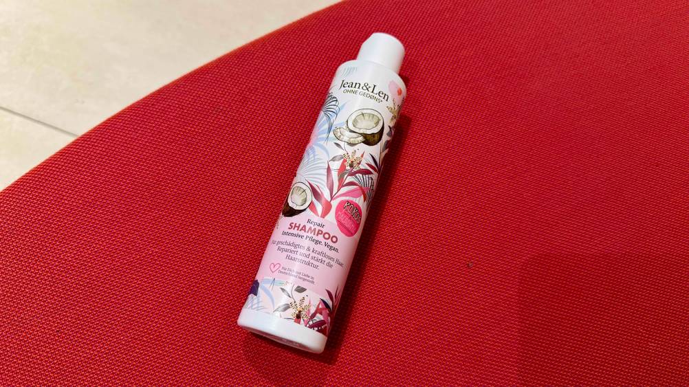 Auf einem roten Teppich liegt eine Flasche des Kokos-Shampoos im Test.