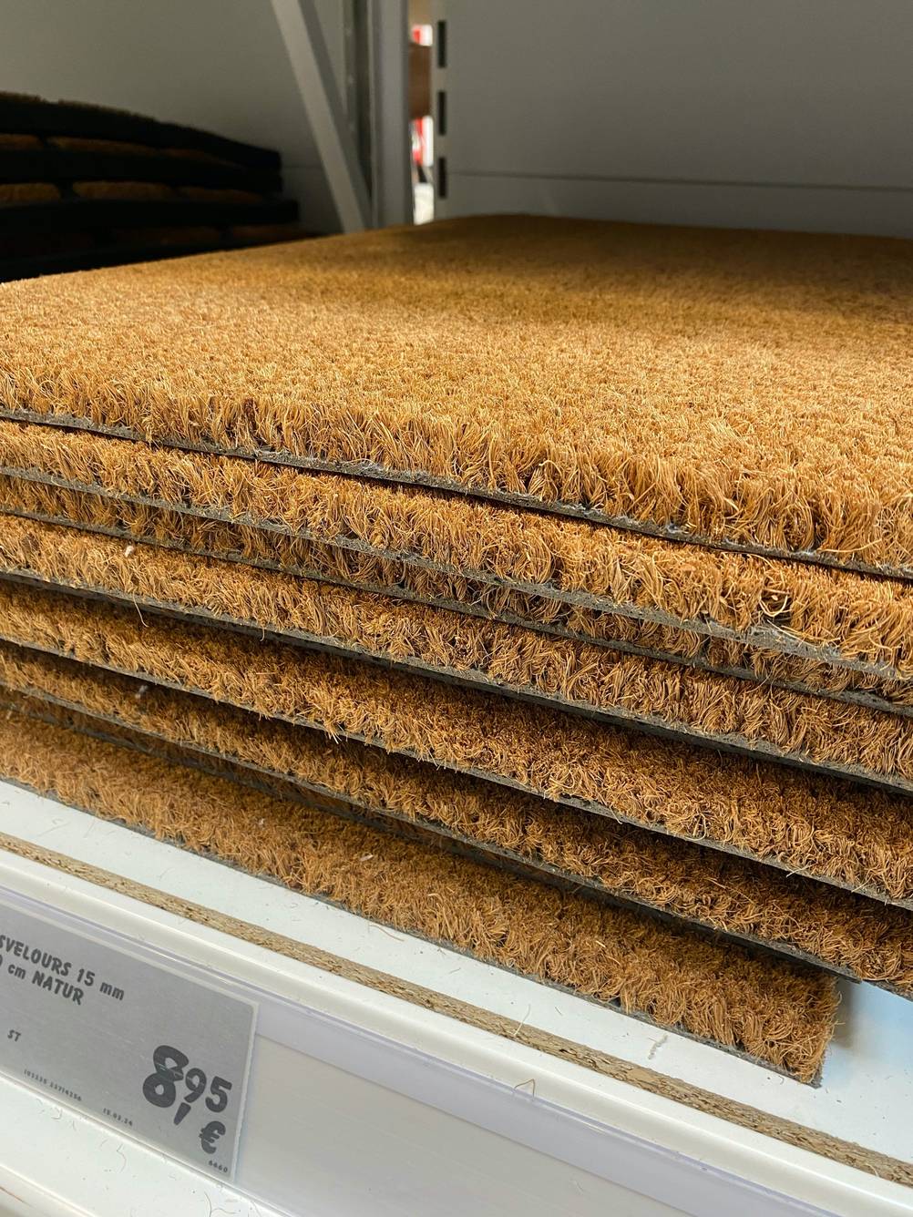 Mehrere getestete Kokosmatten übereinander in einem Verkaufsregal mit Preisangaben.