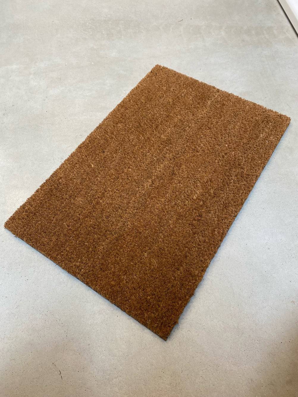 Eine getestete braune Kokosmatte auf einem Betonboden.