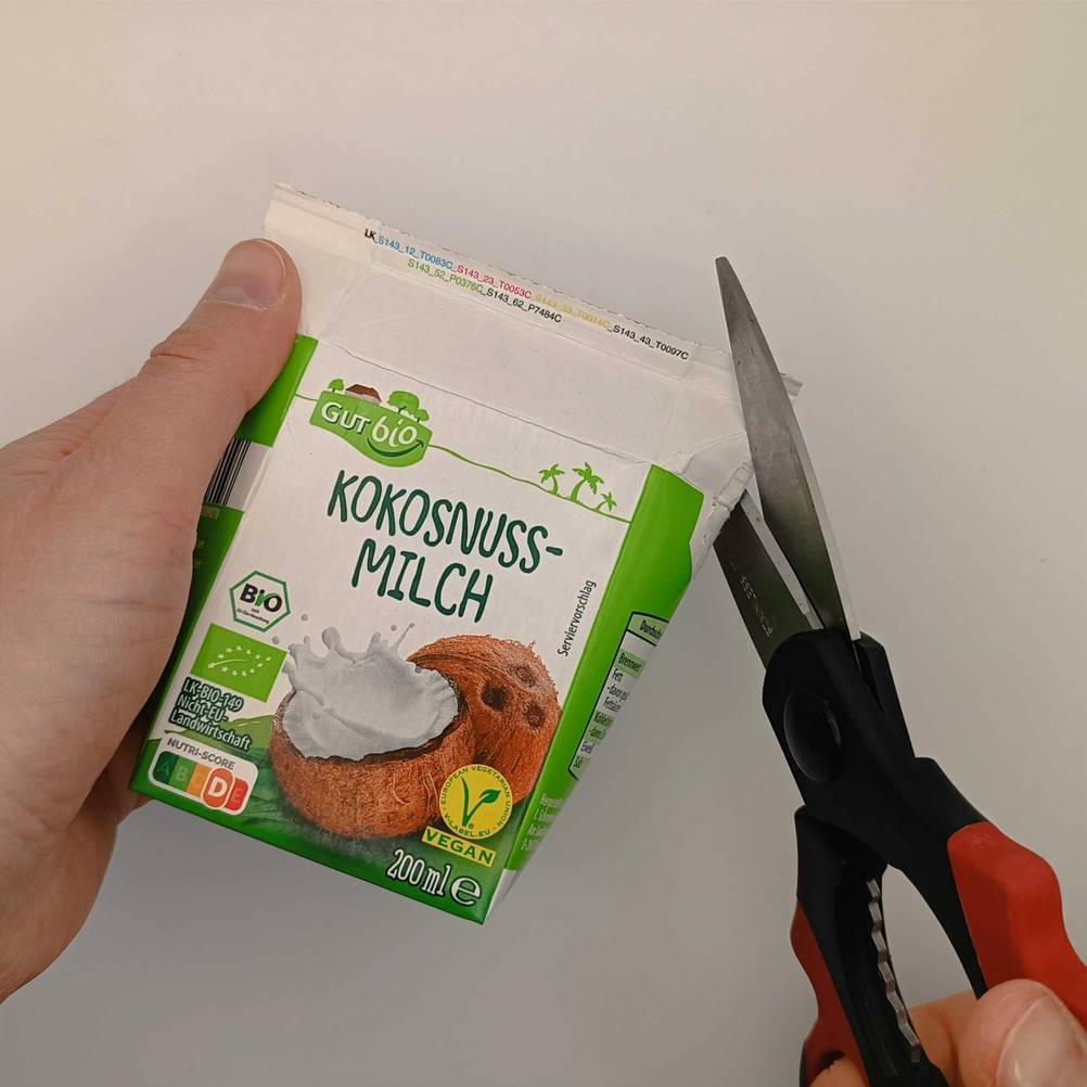 Ein Messer öffnet eine getestete Kokosmilch-Packung. 