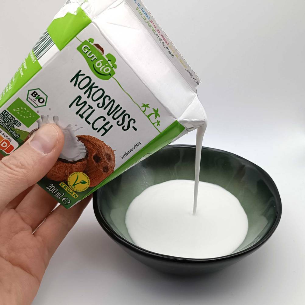 Eine Hand schüttet die getestete Kokosmilch in eine Schüssel.