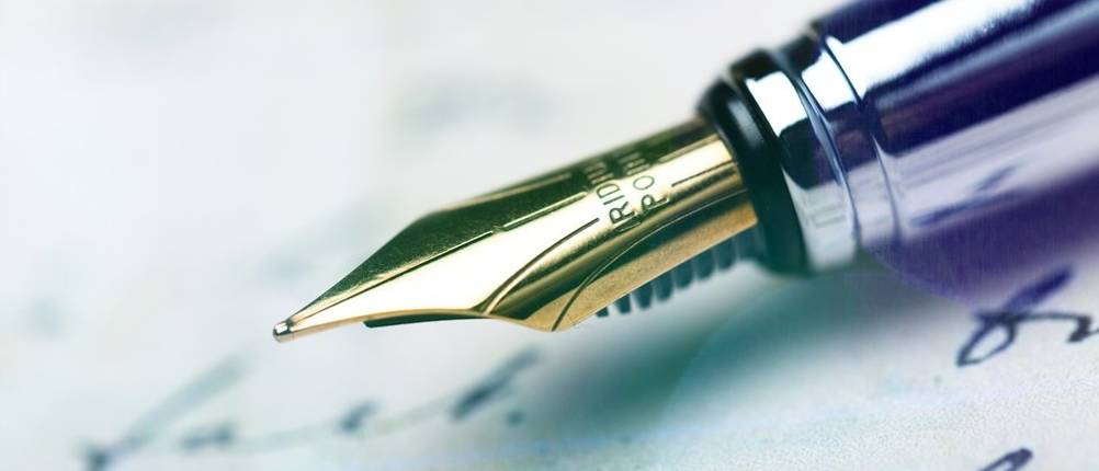 Kolbenfüller-Test: goldene Feder eines Kolbenfüllhalters über Schriftstück