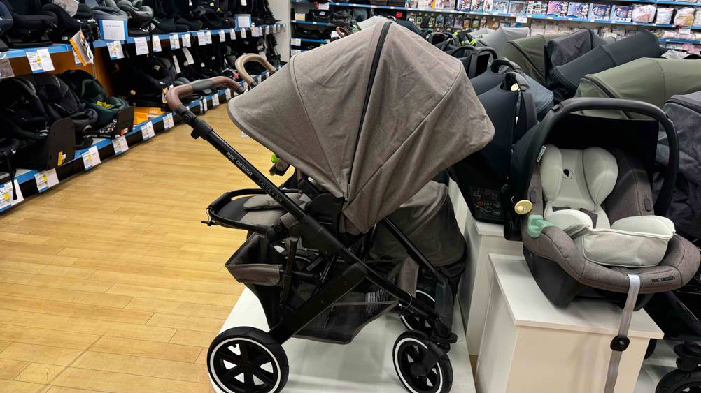 Ein getesteter Kombikinderwagen von der Seite mit geschlossenem Verdeck in einer Ausstellung neben anderen Produkten.