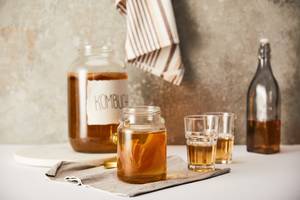 Kombucha-Pilz-Test: Auf einer Küchenfläche stehen mehrere Gläser mit Kombucha. 