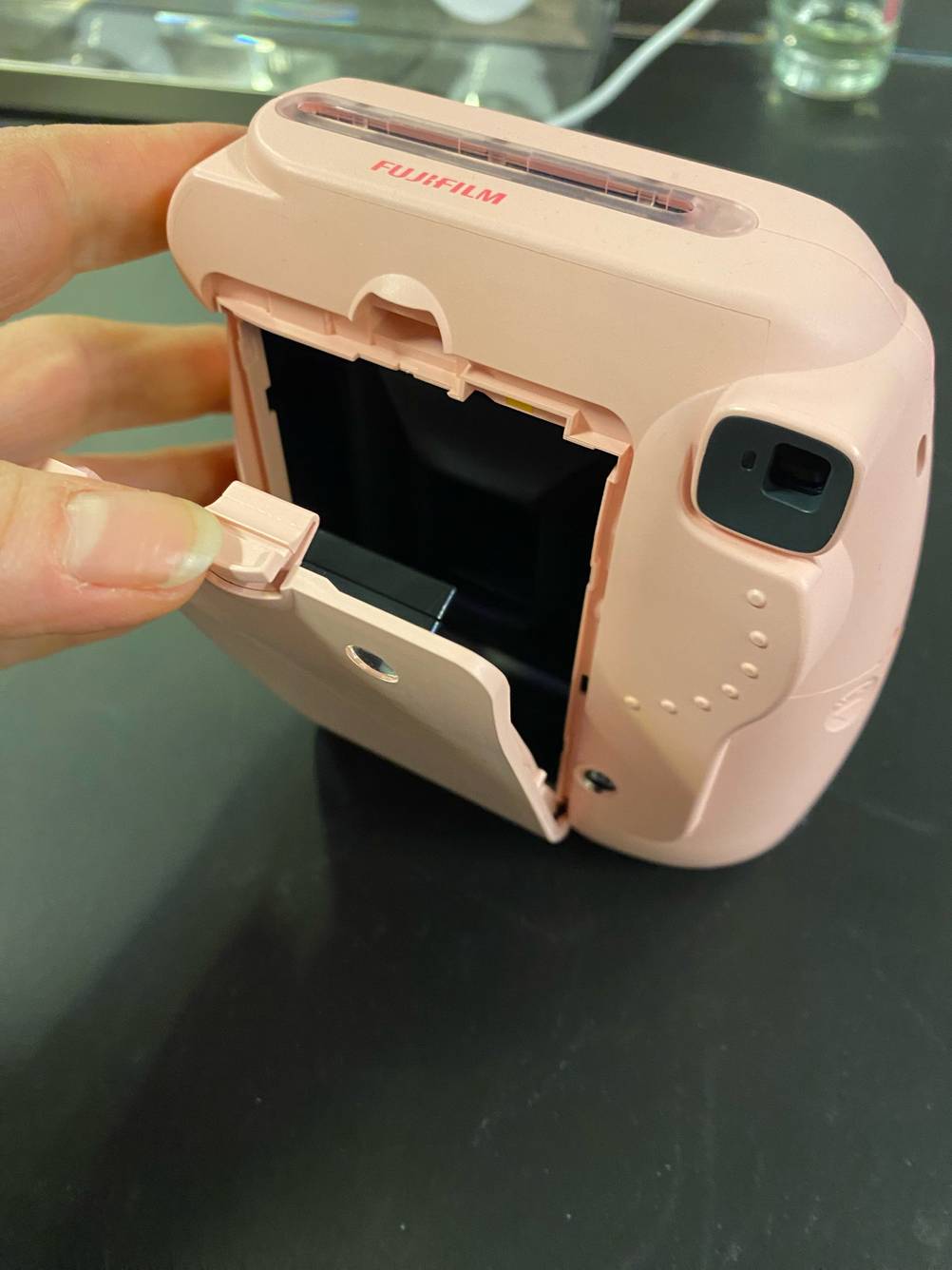 Kompaktkamera getestet: Eine Hand öffnet eine Klappe auf der Rückseite.