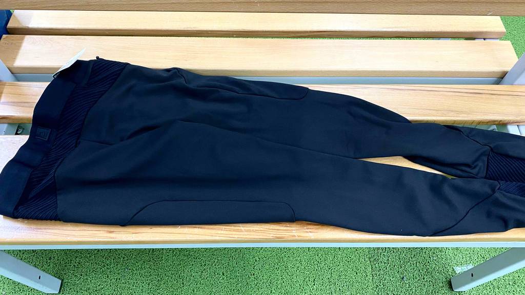 Auf einer Holzbank liegt eine getestete Kompressions-Laufhose für Herren.