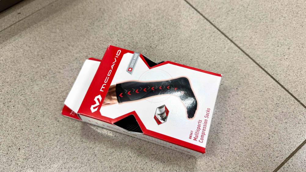 Auf einem Fließenboden liegen die Kompressionsstrümpfe im Test in der Verpackung.