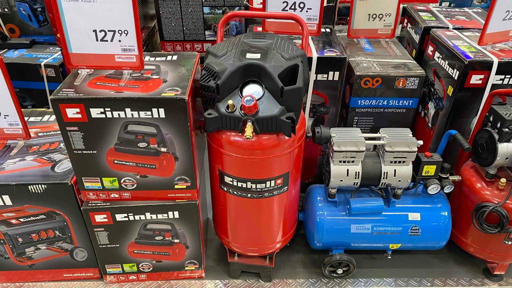 Ein Kompressor stehend steht zum Testen zwischen anderen Geräten in einem Verkaufsraum.