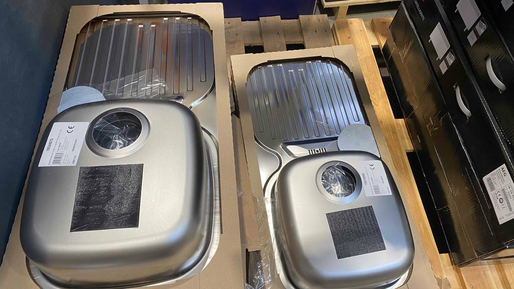 Edelstahlspülen im Test: zwei in Karton verpackte Edelstahlspülen liegen nebeneinander, mit Ansicht auf den unteren Bereich auf einer Holzpalette.