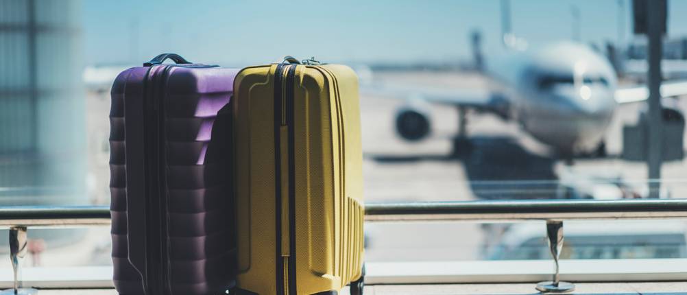 Kono-Koffer im Test: Ein violetter und ein goldener Koffer stehen am Flughafen.