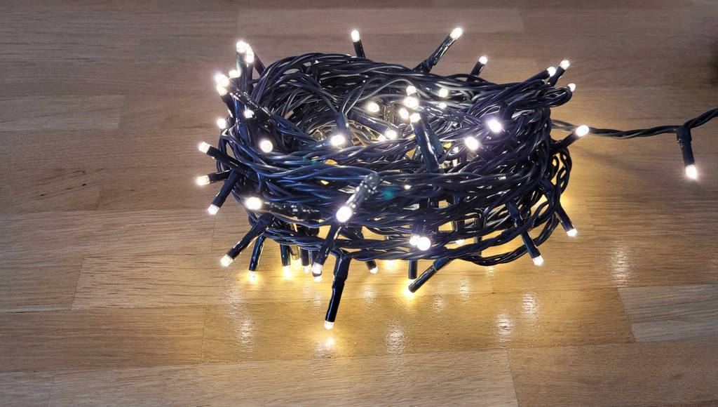 LED-Weihnachtsbeleuchtung im Test: eine zusammengerollte leuchtende Lichterkette liegt auf Laminat.