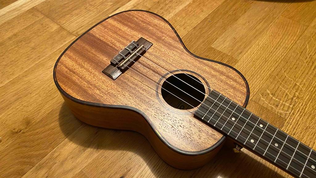 Auf dem Boden befindet sich eine getestete Konzert-Ukulele mit 4 Saiten. 