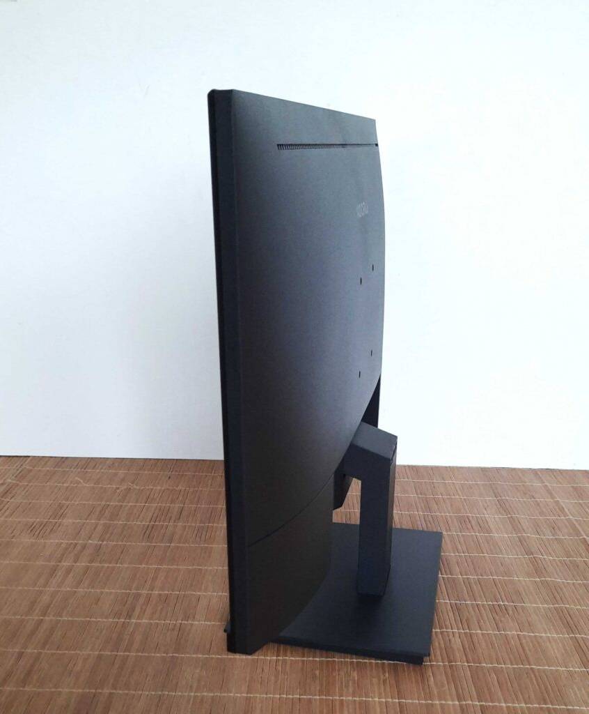 Seitenansicht eines getesteten 24-Zoll-Monitors auf einer Bast-Unterlage vor weißer Wand.