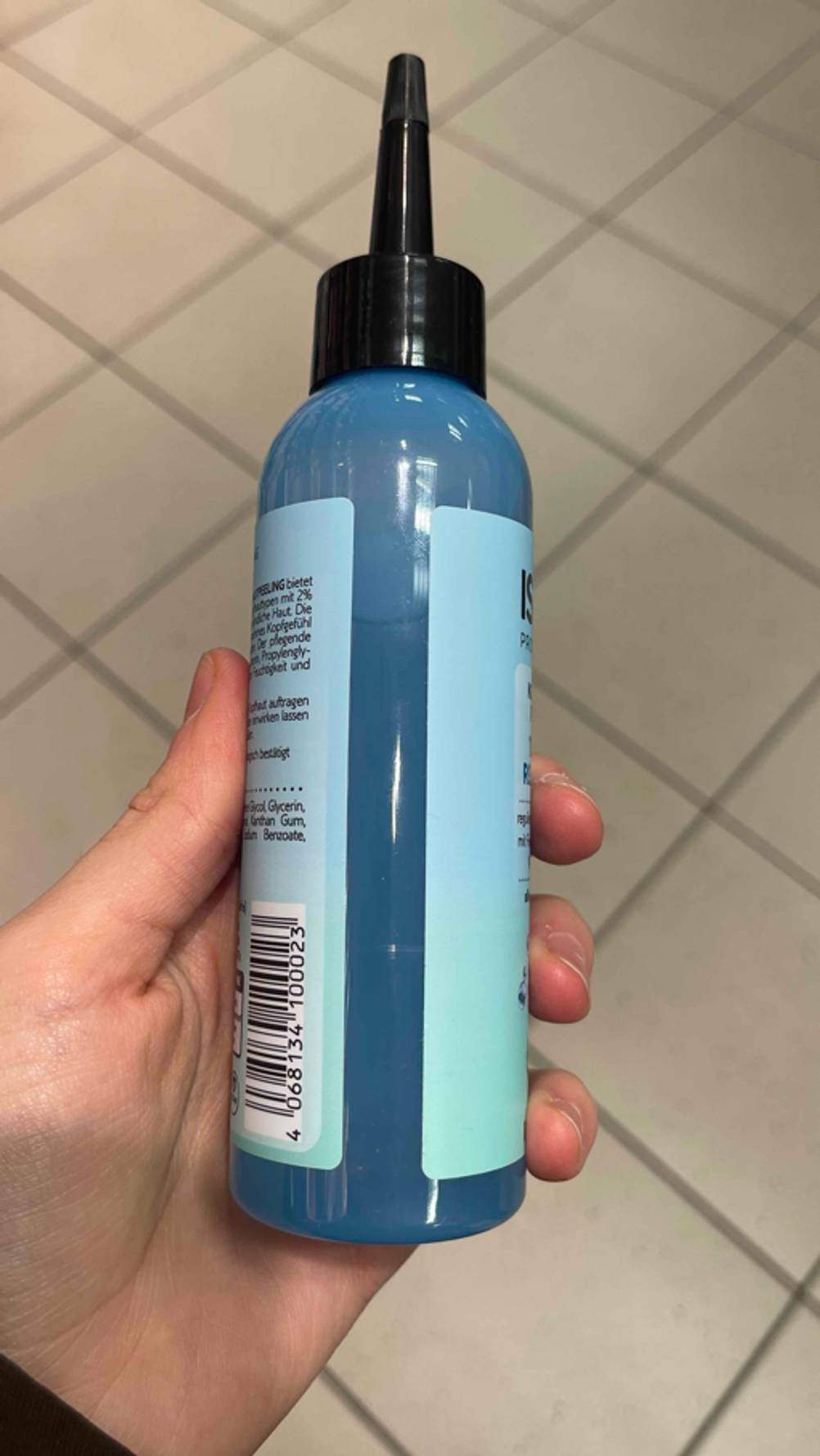 Eine Hand hält die Flasche Kopfhaut-Peeling im Test, die Füllmenge ist zu sehen.
