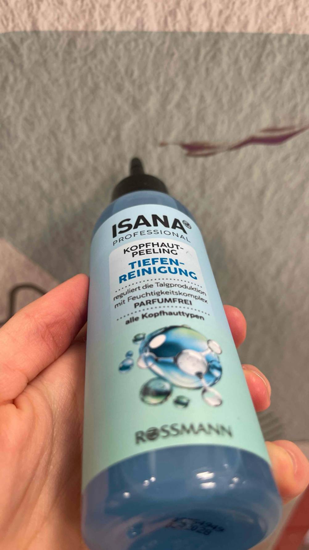 Das getestete Kopfhaut-Peeling von einer Hand gehalten.