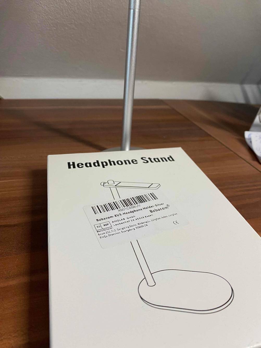 Verpackung von einem getestetem Kopfhörerständer befindet sich auf einem Holztisch.