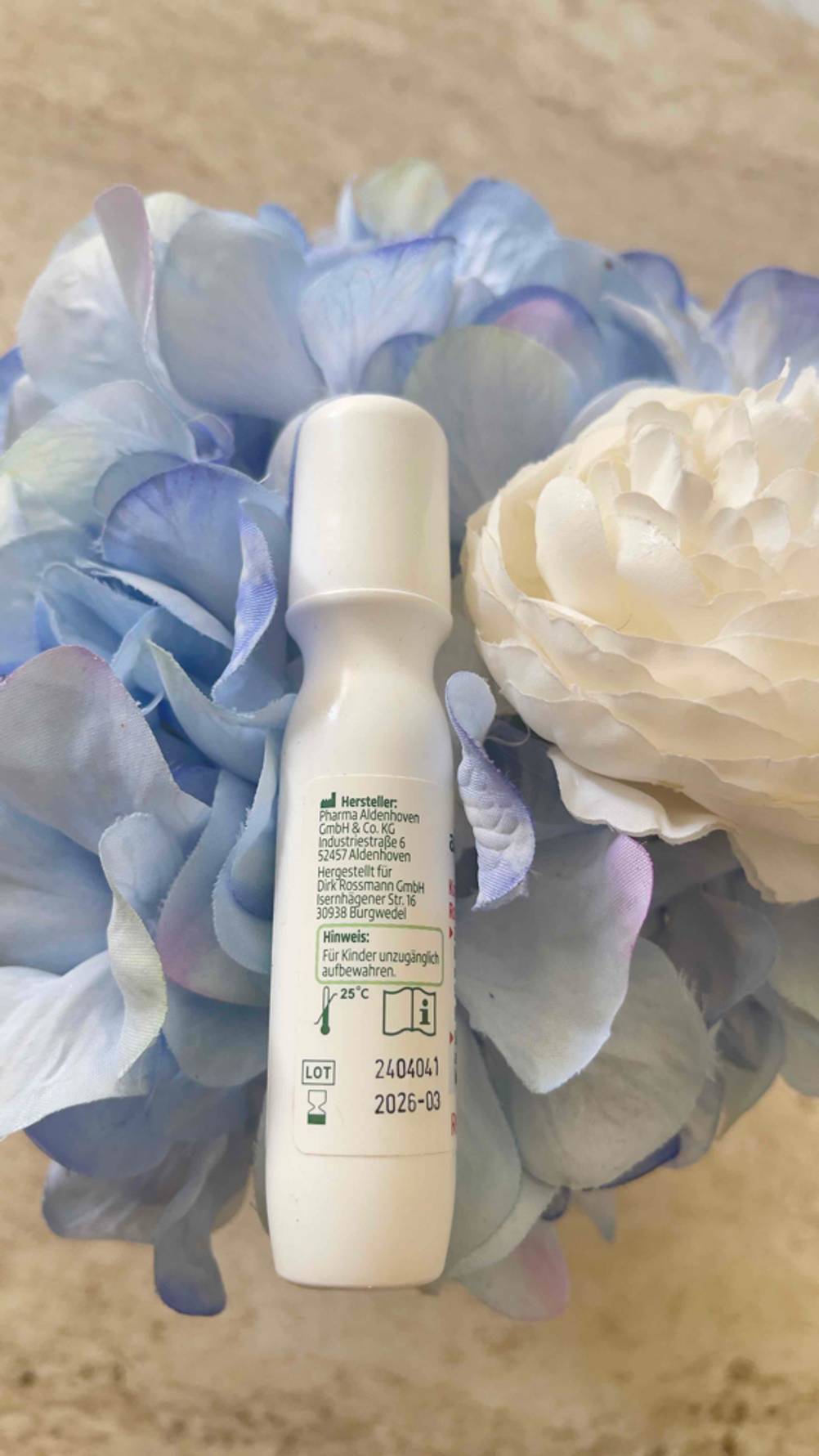 Kopfschmerz-Roll-on im Test: Der Roll-on mit der Rückseite nach oben liegt in einer Plastikblume.