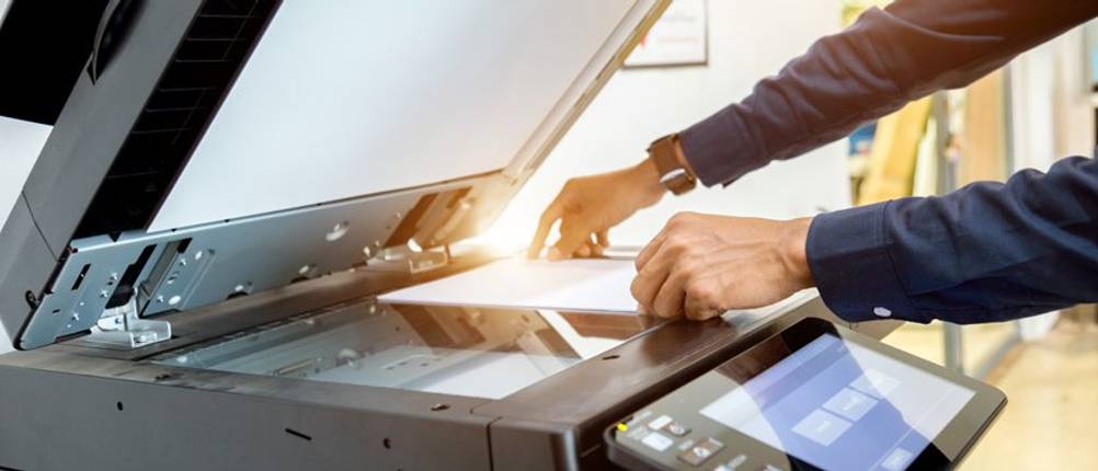 Kopierpapier-A4-Test: Mann greift nach Papier auf einem Drucker.