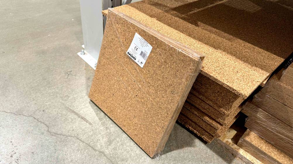 Korkboden im Test: Korkboden-Platten lehnen an einem Stapel mit anderen Platten.