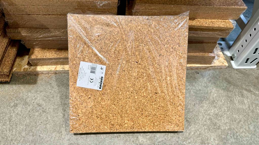 Korkboden getestet: Ein transparent verpacktes Packet von vorne lehnt an einem Stapel.