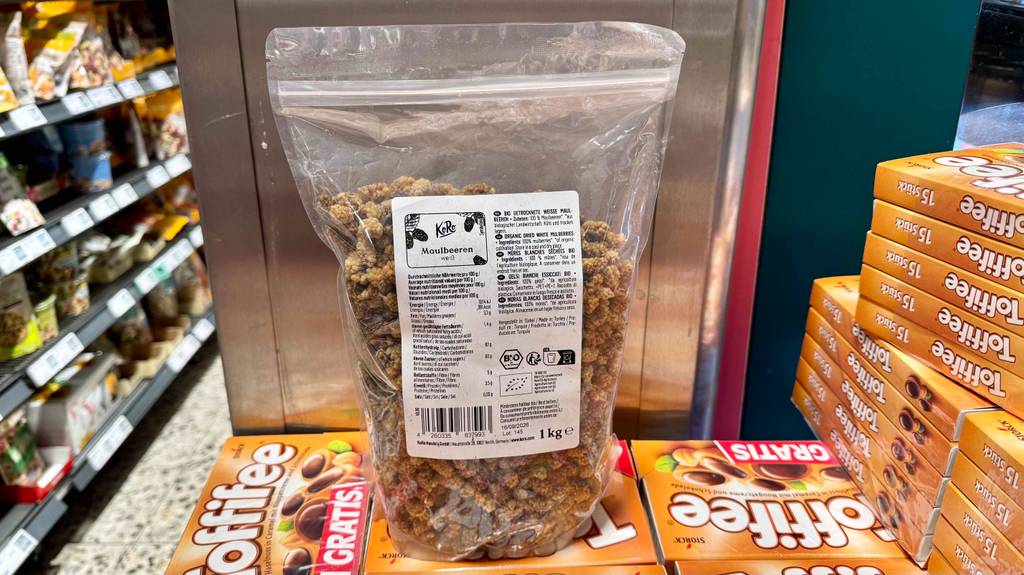 Eine 1 kg-Packung Maulbeeren getrocknet stehen zum testen auf einem Stapel Toffifee.