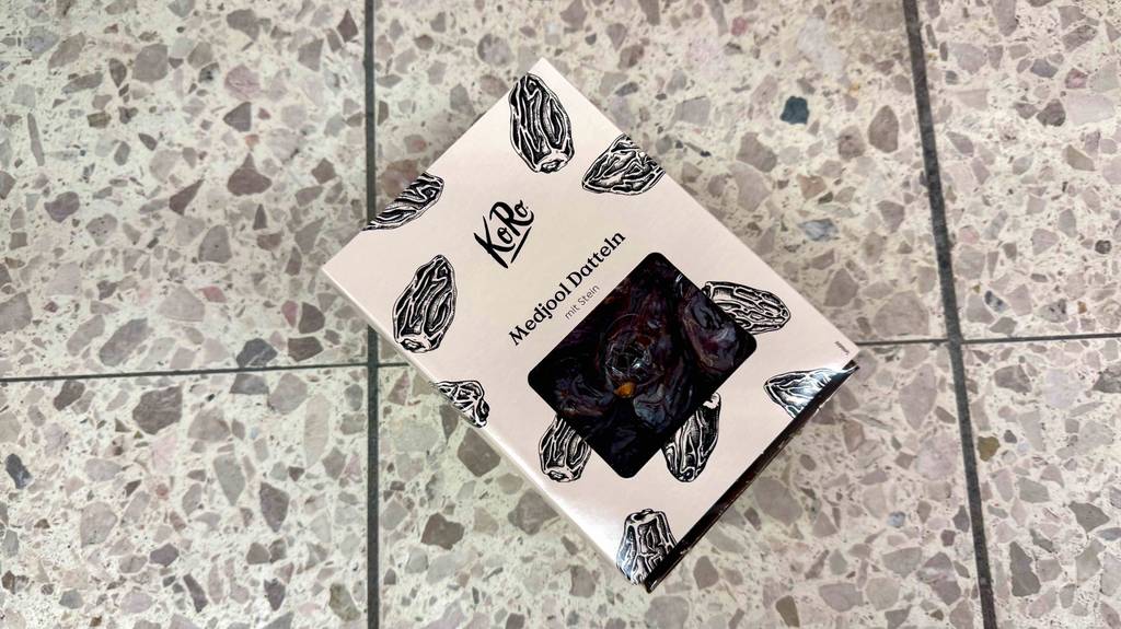 Eine Packung Medjool-Datteln liegt zum testen auf einem Fliesenboden.
