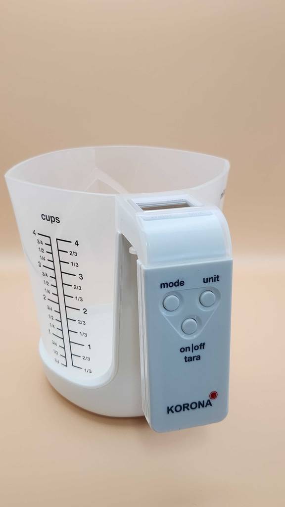 Ein Messbecher mit Waage im Test steht auf einer beigefarbenen Oberfläche.