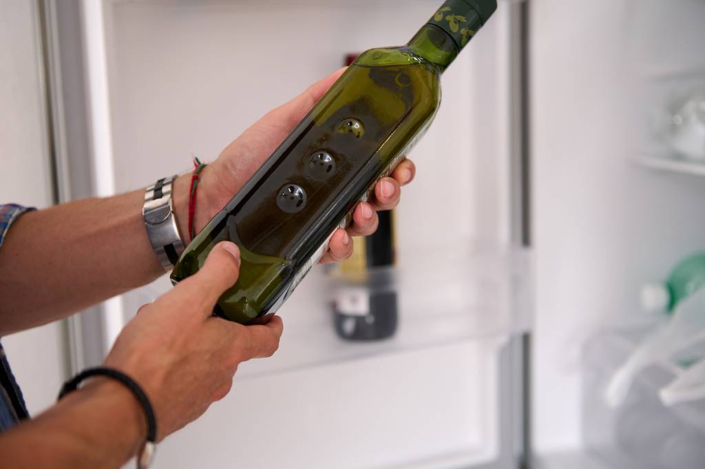 Koroneiki-Olivenöl-Test: Ein Mann betrachtet das Etikett einer Olivenöl-Flasche. 