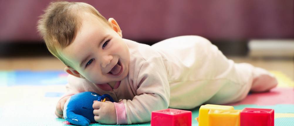 Sweet Smiling Baby Boy Crawling And Playing With Toys On Carpet
