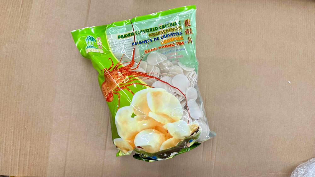Auf einem Karton liegt eine Packung der getesteten Krabbenchips.