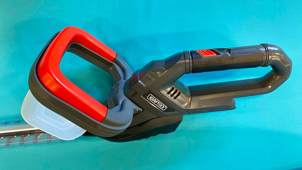 Nahaufnahme des Motors und des Griffes einer getesteten Akku-Heckenschere auf blauem Grund.