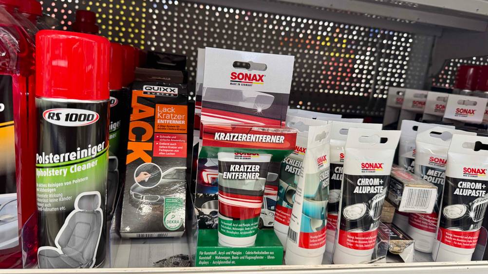 Mehrere originalverpackte Kratzer-Entferner stehen in einem Verkaufsregal neben anderen Produkten.