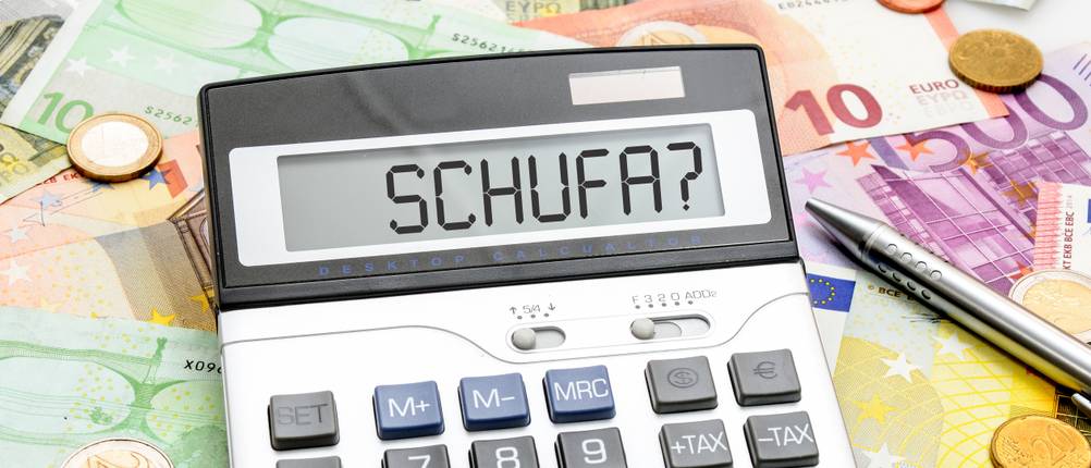 Kredit-ohne-SCHUFA-Test: Ein Taschenrechner liegt auf mehreren Geldscheinen und zeigt im Display 